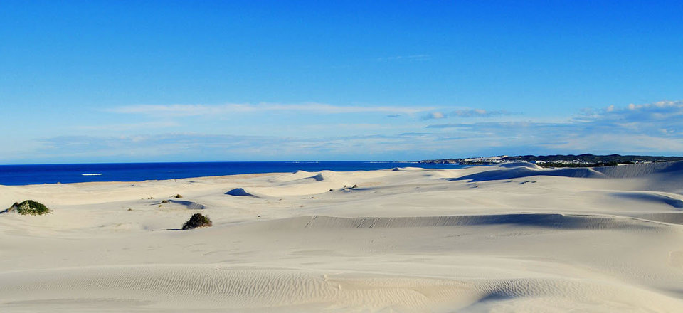 Discover a Village Caught Between Golden Sand Dunes and Deep Blue Sea