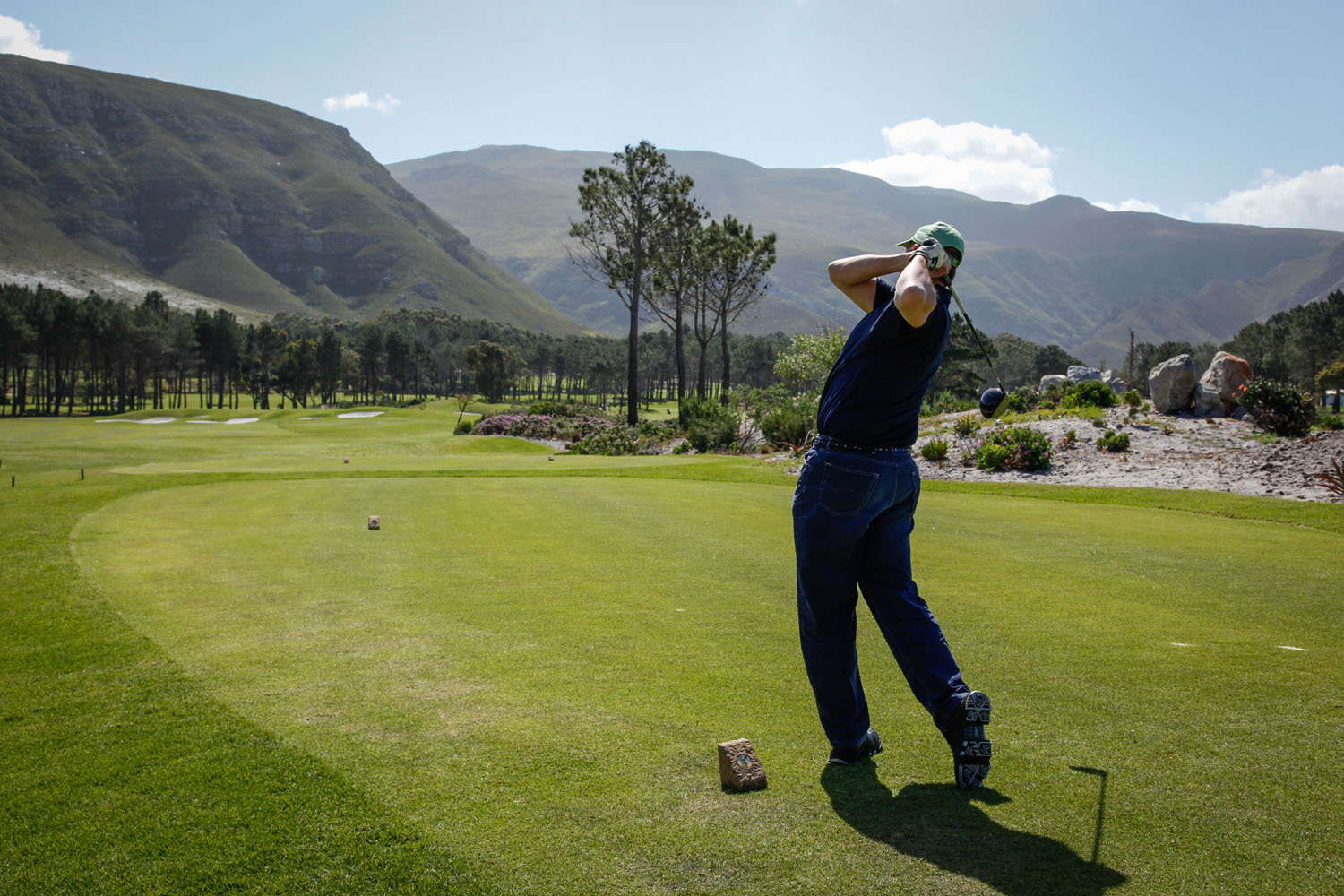 A golfer teeing off on a golf course in Hermanus, close to Hermanus Heights