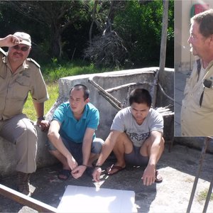 DAFF Inspekteur Hennie Smit van DAFF hou toesig oor die twee Chinese verdagtes. Inlas: Johan Rademeyer.