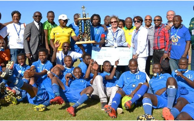 Kameraadskap en Sport wen weer eens by die onlangse Overstrand Burgemeesterssportfees op die Zwelihle Sportgronde. In die middel staan die Mighty Blues Mens Sokkerspan se trotse kaptein, “Buddy” met die gesogte trofee wat deur hulle gewen is. Links van hom is Masizole Mnqasele (MPP) en regs is Overstrand se Uitvoerende Burgemeester, Raadsdame Nicolette Botha-Guthrie.
