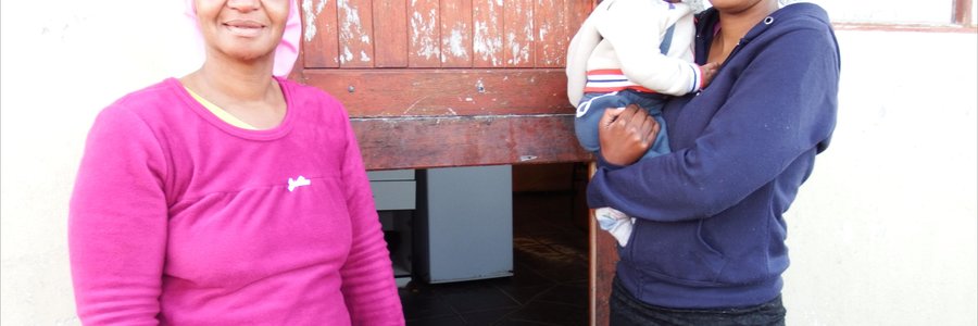 Vlnr is Elsa Europa en Elwida Damons en haar baba van drie maande, met  klein  Waldy Europa wat voor sit, by die agterdeur van Elsa se woning waarvan die onderste helfte uitgebreek is