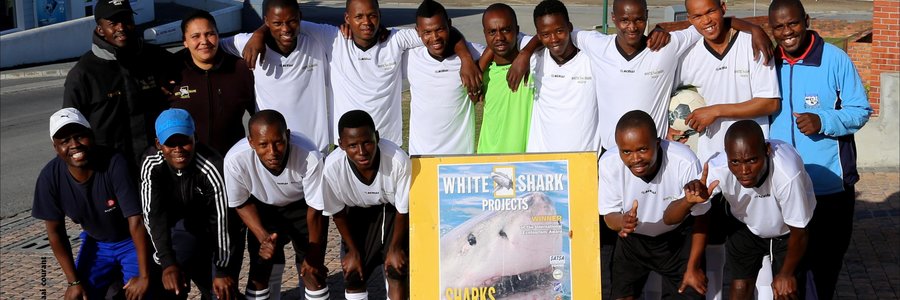 Masakane’s Eastern Cape United soccer team played in the local league for the past two seasons.  In the first season, the team finished 14th out of 17 teams and in the second season bettered itself to a number seven position. They were privileged to receive brand new outfits from White Shark Projects (WSP) previously.  Natasha Smith from WSP appears here with Mandlonke Ngazini (middle) who initiated the sponsorship and who is working at WSP for the past thirteen years.  Mr Ngazini said that the main objects are to keep the youth off the streets and to fight against drug abuse through healthy sport participation.  He thanked White Shark Projects for the generous sponsorship.  Anyone interested in participating in any of Eastern Cape United’s team efforts can contact the Chairperson, Mr Mhlaba at 0735771207.