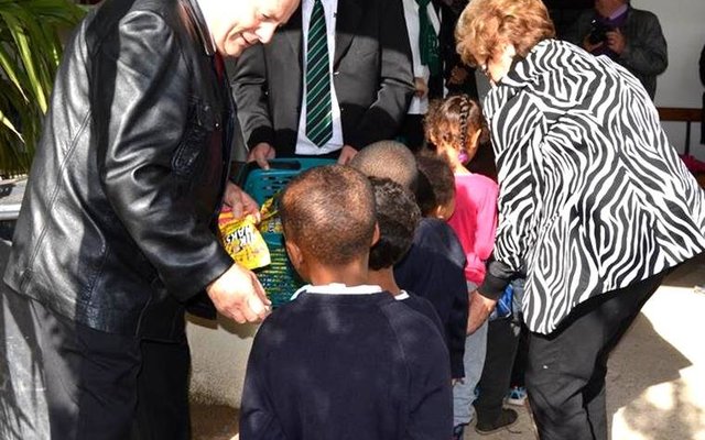 AVBOB Group CEO, Frik Rademan (left) and Overstrand Executive Mayor, Nicolette Botha-Guthrie (right) pictured handing out goody bags to learners of The Fynbos Academy, while AVBOB’s Western Cape Provincial Manager, Johan Tinderholem lends assistance.