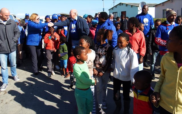 Selfs kinders het opgewonde en al dansende aan Premier Helen Zille se optog in Masakhane se strate deelgeneem. Tweede van links gee Premier Zille en Rdl Dudley Coetzee mekaar ‘n handdruk.