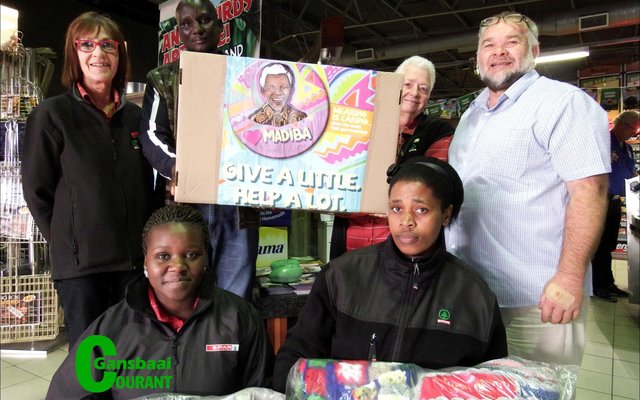Gansbaai Superspar se personeel het onder leiding van Riana Enslin (links) self komberse en mussies gemaak wat aan pastoor Frikkie Zeelie (regs) oorhandig is.