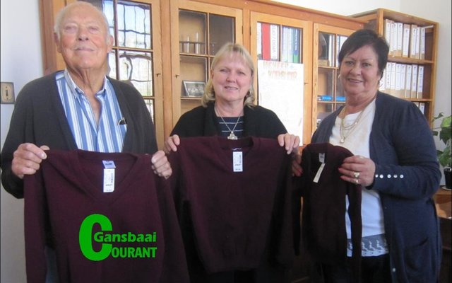 Onderskeidelik links en regs is John en Ivy van Huyssteen van die Gansbaai Lions Klub, wat twintig skooltruie aan me. Haxton (middel) van laerskool Okkie Smuts oorhandig het.