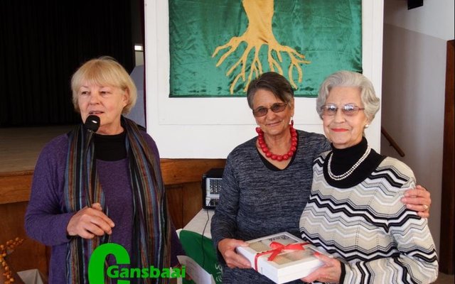 Trudie du Plooy (regs) ontvang haar geluktrekkingsprys tydens die enkellopendes se byeenkoms van Alta van der Westhuizen, met Francia van Dyk by hulle.