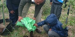 Benjamin Kondokter wys leerders van Masakhane Primary School hoe om bome te plant.