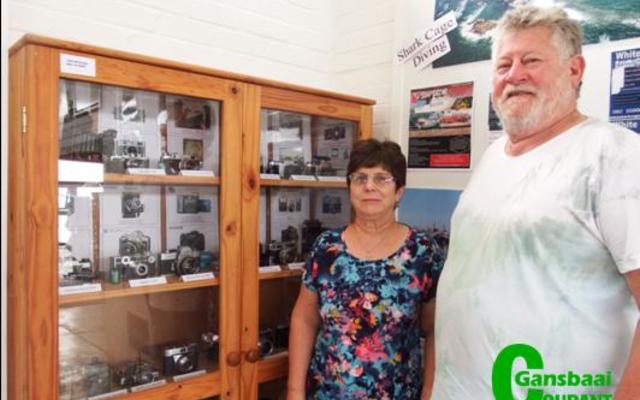‘n Veteraan kamera-uitstalling in Gansbaai Toerisme se uitstallingslokaal wat die moeite werd is om te besoek. Vlnr Glenda Kitley (Bestuurder: Gansbaai Toerisme) en die uitstaller, John McGregor.