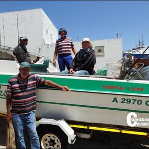 Skipper Jean Downing staan voor sy boot, Relêks II, met sy bemanning vlnr op die boot Bertus Prins, George Rowan en Philip Fourie ná hulle hengeldag op see.