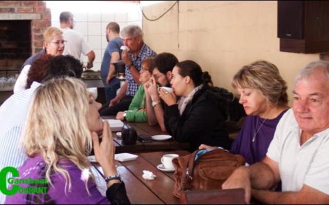 Gesellige samesyn tussen familie en vriende wat gesellig verkeer met die hardwerkende braaiers in die agtergrond.  