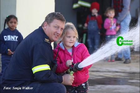 Gansbaai se nuut bevorderde senior brandweerman, Gallie Badenhorst het Woensdagoggend vir die kleuters van Kleine Gansies gewys hoeveel krag ‘n mens moet hê om ‘n brandslang vas te hou.  Die 5-jarige Layla Wessels kry dit sowaar reg.  