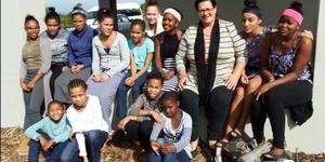 Die Herberg Kinderhuis se huismoeder, Bettie Thomas (3de van regs), word hier omring deur Huis E se dogters op die stoep van die gastehuis terwyl hulle vir hul Sondagmiddagmaal wag.