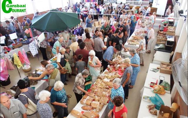 ‘n Geheelbeeld van die gesellige basaar, met stalletjies in die sy-saal en buite op die terein.