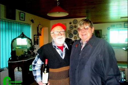 Links ontvang die 91-jarige kaptein Willem van der Merwe sy bottel rooiwyn met die eiendomsagentskap se etiket daarop, van Petrus du Preez, die agent wat die transaksie beklink het.  Petrus self raak-raak aan 80 jaar. 