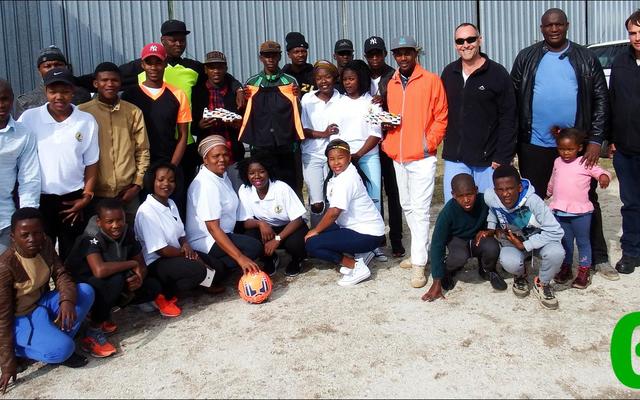 Solyx United sokkerspan glimlag breed oor hul nuwe uitrustings en sokkerballe, geborg deur Solyx Films SA. Van regs is Jacques van Lill (ontwikkelingsprogram), Thebelani Xovula (voorsitter) en Peter Huyser van Solyx Films, met ‘n groepie kinders wat reeds die sokkerballe “ingewy” het.