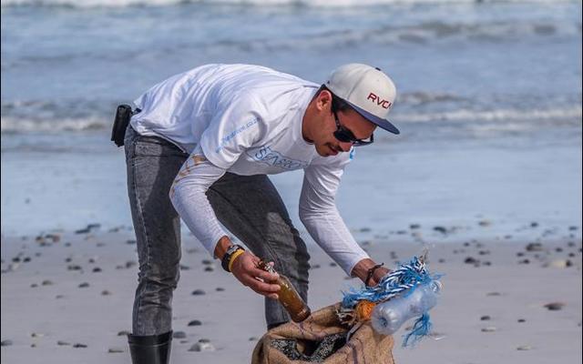 A volunteer taking part in the clean up day from Franskraal to Die Gruis collects a bottle. It is estimated that approximately 635,000  tonnes of rubbish enters our oceans every year.