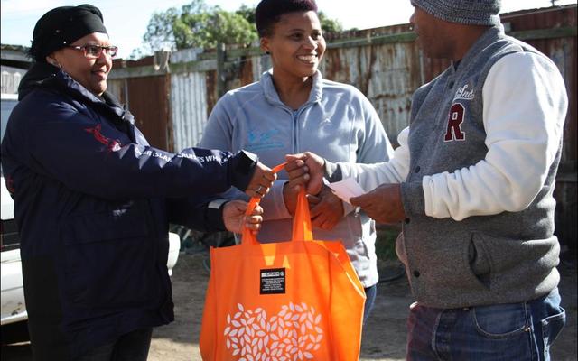 Pinkey Ngewu (DICT) together with Belnay van Tonder (Great White House) handing over a food parcel gift to 1st year DEEP student Vanashree Lottering’s dad.