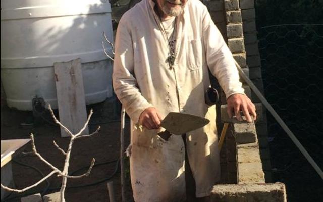 Oom Koos Groenewald waar hy besig om die muur agter sy huis klaar te bou. Hy het sy hele huisie waar hy nou rustig woon, eiehandig sonder hulp gebou.