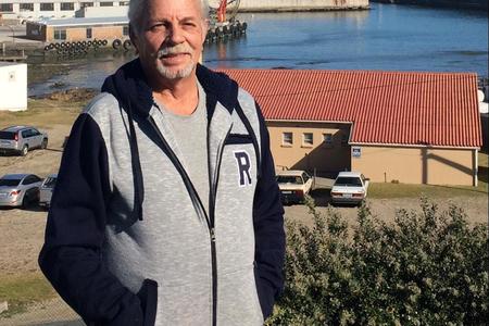 Faan Buys, Head Mechanical Engineer for Dyer Island Fisheries with the Gansbaai Harbour and factory in the background.