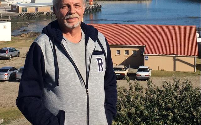 Faan Buys, Head Mechanical Engineer for Dyer Island Fisheries with the Gansbaai Harbour and factory in the background.