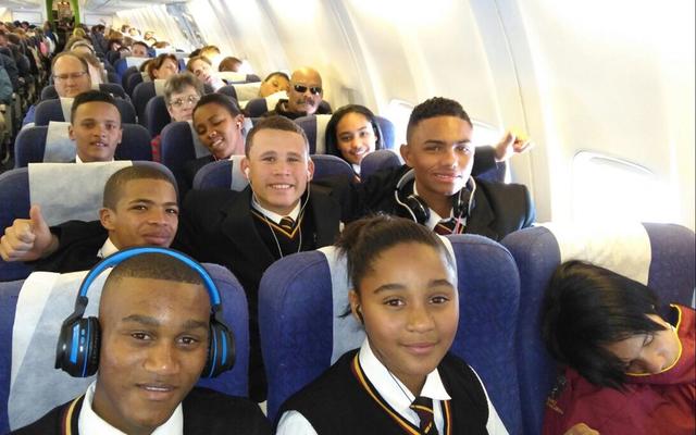 In die vliegtuig, vir almal ‘n eerste keer, op pad na Johannesburg. Van links: 1ste ry Sebastian Johnson, Daylen Tobias en Kaylin Robertson (klaar aan die slaap!); 2de ry Jaygon Visagie, Izaan Newman en Lorenzo Geldenhuis; 3de ry Ulrich Visagie, Simorné Europa en Heidri Loff; 4de ry regs is Aletta Groenewald (hulp) en Tommy Wilson (skoolhoof).