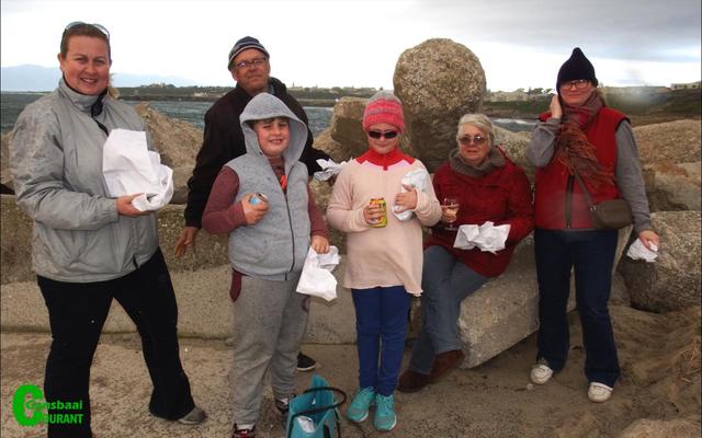 Hierdie twee gesinne met hulle vis & skyfies sê dit was die moeite werd om die reën te trotseer tydens Gansbaai Toerisme se “Sunset Walk”. Voor van links is Luke Devitt, Emily Kellerman, Anmarie Watney en Justina Kellerman. Agter is Carol en Wayne Devitt.