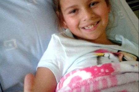  ‘n Moedige klein Carli Swart (7) wys hier met haar duim opwaarts vanuit haar hospitaalbed in die Louis Leipoldt Hospitaal dat sy sommer baie goed voel na die vorige dag se operasie. 