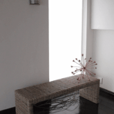 A woven bench provides a view of the garden through the full-height window as you enter Xairu.